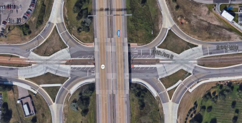A bird’s-eye view of a diverging diamond interchange in Bloomington, Minnesota. Two diamond-shaped formations of many converging and diverging lanes of traffic are seen on either side of a multilane highway.