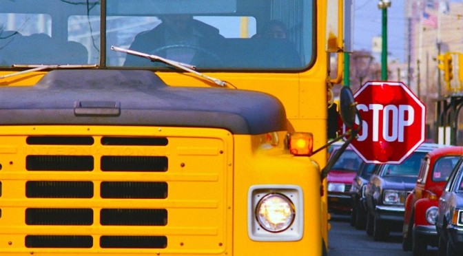 School bus with stop arm extended on busy street